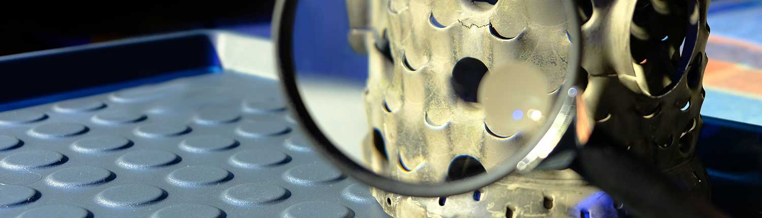 Werkstück wird mit Vergrößerungsglas geprüft - Sichtprüfung